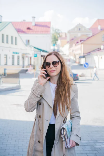 Mujer de moda caminando y hablando en el teléfono móvil en una calle de la ciudad —  Fotos de Stock