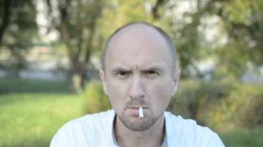 kel adam yaz parkı portre sigara içiyor