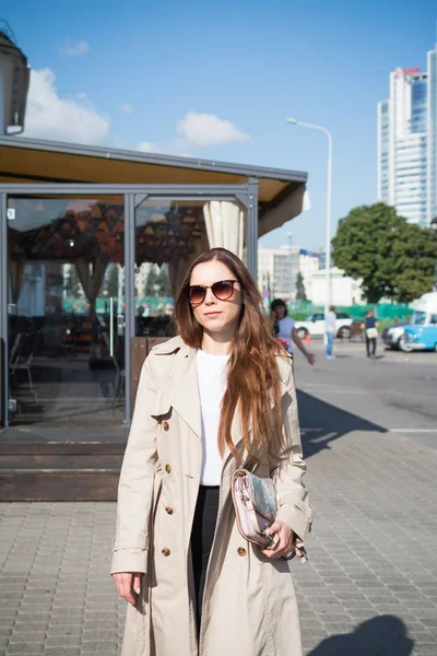 şık genç kadın güneşli bir sonbahar gününde şehrinin sokaklarında yürüyor