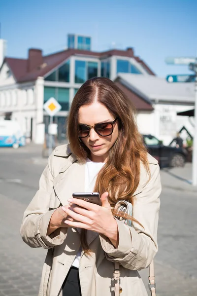 Mujer joven y elegante está caminando por la calle y hablando por teléfono — Foto de Stock