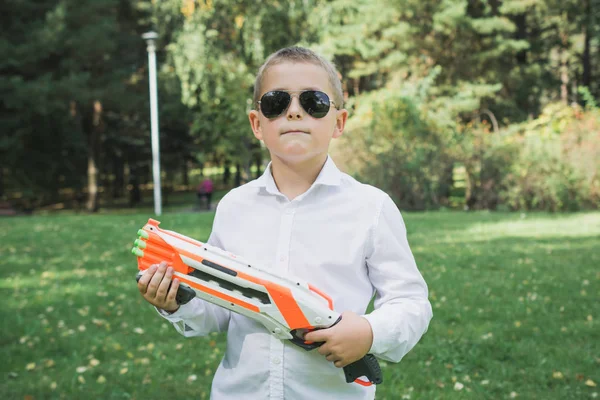 おもちゃの銃を持つ美しい8歳の少年. — ストック写真