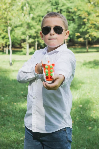 おもちゃの銃を持つ美しい8歳の少年. — ストック写真