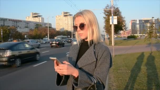 Mooi blond meisje is bellen via telefoon en mobiele applicatie taxi — Stockvideo