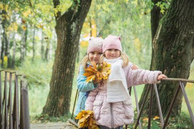İki kız kardeş, kuzenler, sonbahar parkında yürüyorlar.