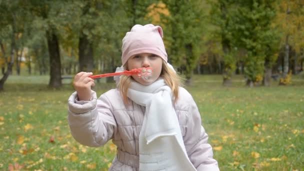 Portret zabawnej dziewczynki dmuchającej bańki mydlane — Wideo stockowe