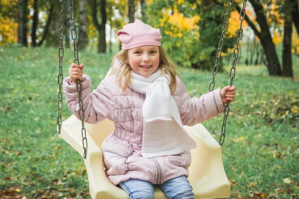 Niña de 5 o 6 años balanceándose en un columpio contra el fondo de un niño — Foto de Stock