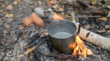 Kamp gezisinde yemek pişirmek, bardakta su ve kömür sosisi.