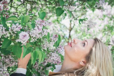 Bir kadının hassas portresi çiçek açan leylak çalılarının arka planında