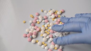 Doktorlar beyaz arka planda hapları ayıran mavi eldiven veriyorlar.