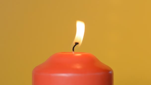 Llama de vela roja sobre un fondo amarillo — Vídeo de stock