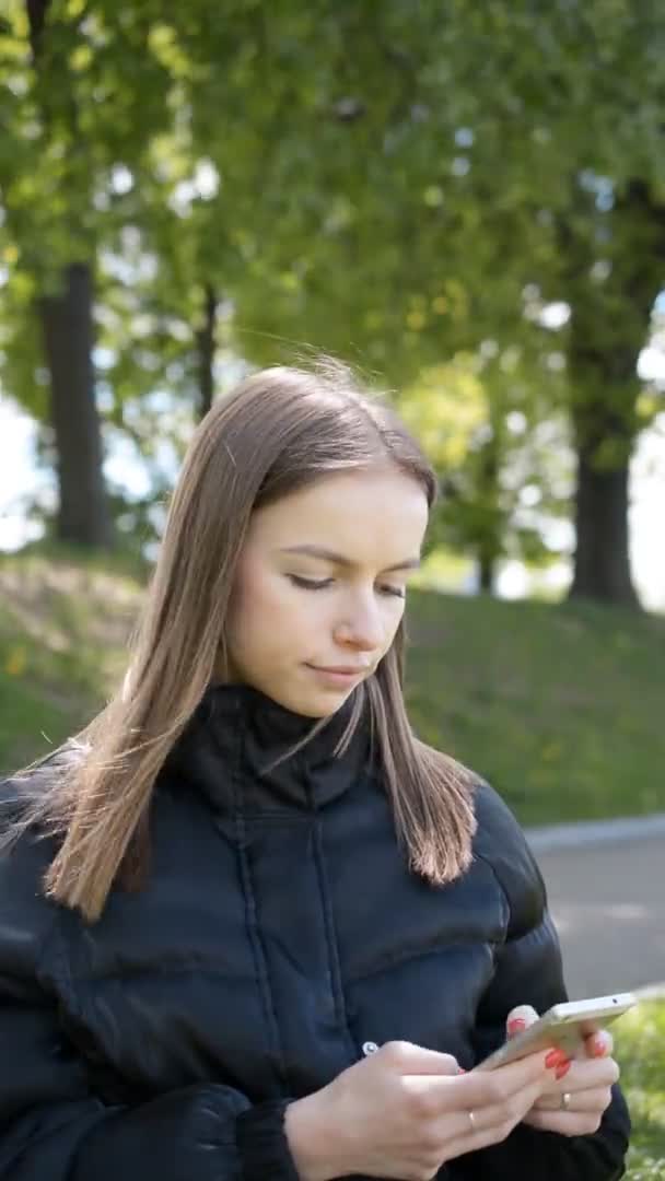 Hermosa joven escribe un mensaje en un teléfono inteligente — Vídeos de Stock