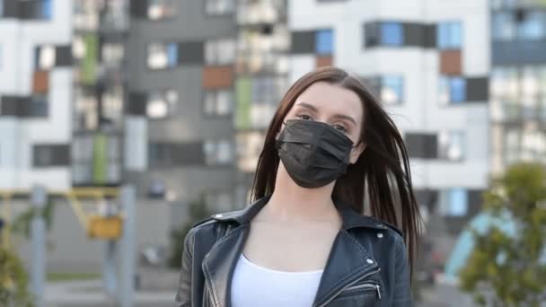Portré egy barna lány egy védő maszk fekete háttér egy modern lakossági negyed a városban — Stock videók