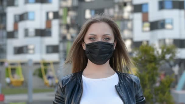 Calle de la ciudad al aire libre caucásico Retrato de una mujer con una máscara negra mirando a la cámara — Vídeos de Stock