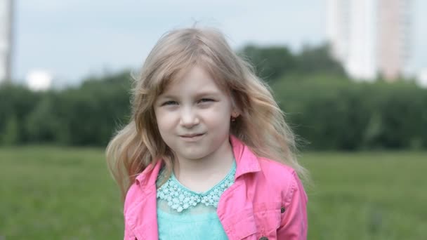 Mała dziewczynka pięć lat portret w różowym dżinsowej kurtce na łonie natury patrzy w aparat — Wideo stockowe