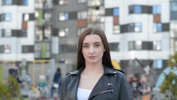 Stílusos fiatal barna lány néz szomorú a kamera portré a háttér egy modern lakóövezet — Stock videók