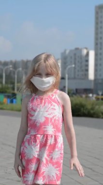 Koronavirüs salgını virüsünden maske takmış küçük bir kız çocuğu kameranın sanal görüntülerine bakar.