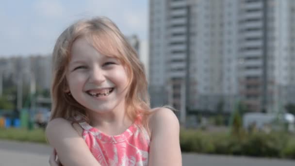 Маленькая девочка смотрит в камеру и смеется на улице — стоковое видео