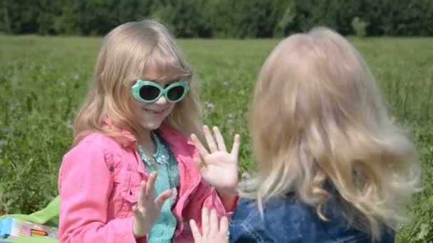 Dos niñas juegan en el parque en la hierba en un día soleado de verano — Vídeos de Stock