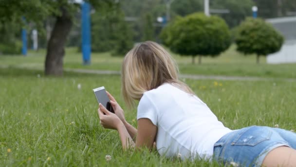 Frau mit blonden Haaren liegt auf dem Rücken im Gras — Stockvideo