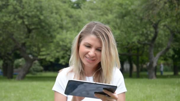 Vista frontal do retrato de mulher caucasiana usando tablet digital no parque da cidade — Vídeo de Stock