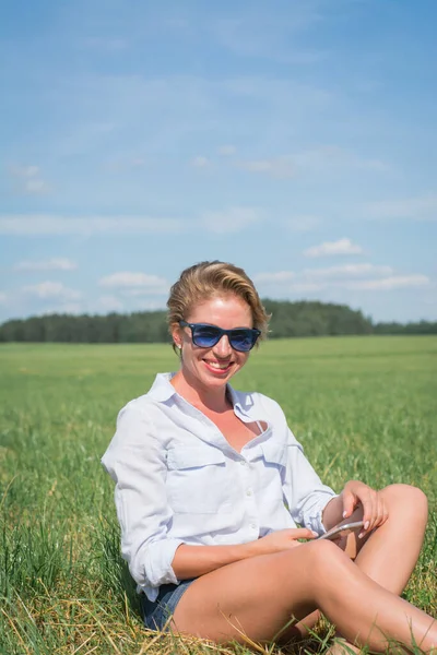 Vacker Kvinna Vit Skjorta Sitter Ett Sommarfält Gräset Med Telefon — Stockfoto