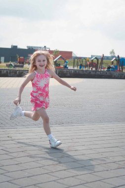 Şirin küçük kız bir yaz günü sokaklarda koşuyor ve eğleniyor.