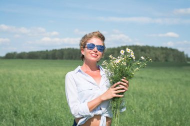 Bir buket papatyayla tarlada güzel bir kız.