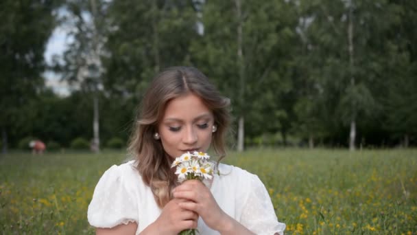 Портрет красивой девушки с маленьким букетом маргаритки в руках — стоковое видео