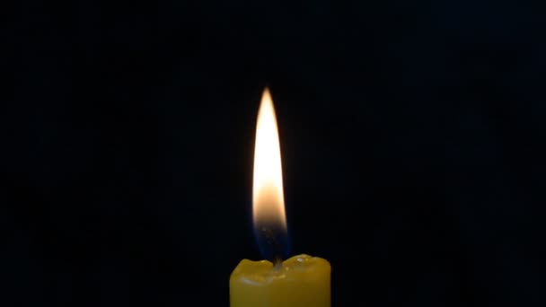 Flamme de bougie sur un fond noir se balançant d'un peu de vent, fond, espace libre pour le texte