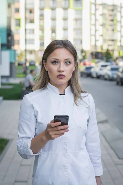 nurse with face mask calling on the phone on a city street