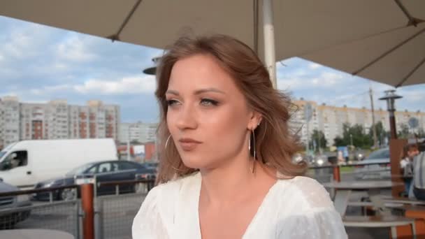Красивый стильный портрет молодой девушки в летнем кафе на закате — стоковое видео