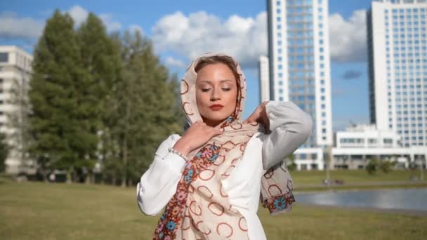 Portret van een stijlvol en elegant jong meisje op straat die een vlot op haar hoofd zet — Stockvideo