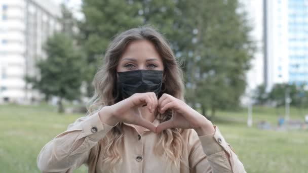 Liebeskonzept, Mädchenporträt in Gesichtsmaske zeigt schlagendes Herz mit Händen — Stockvideo