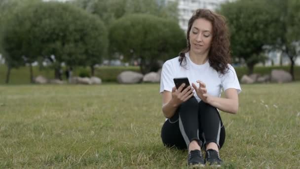 Frau liest auf Smartphone im Stadtpark — Stockvideo