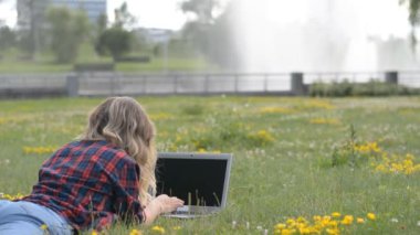Park 'ta serbest çalışmak için bilgisayar kullanan genç bir kadın.