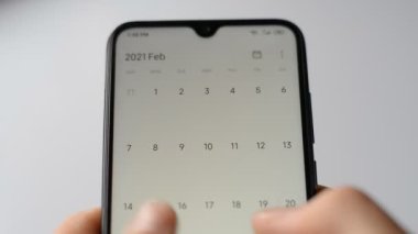 Akıllı telefon takvimi uygulaması kullanan bir adamın elinin yakın plan görüntüsü