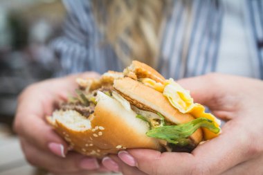 Lezzetli sağlıksız burger sandviçi kadınların elinde.