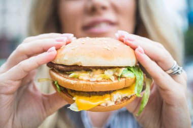 Fast food restoranında elinde çizburger ya da hamburger tutan bir kız.