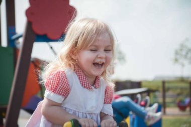 Şirin küçük kız portresi şehir salıncağında oturuyor. Aile sevgisi kavramı