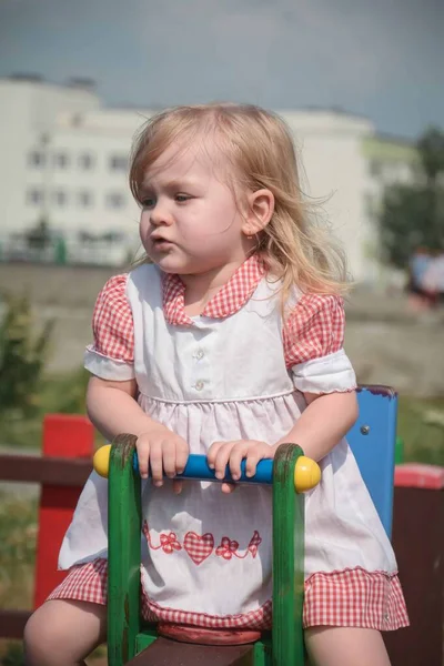 Şirin küçük kız portresi şehir salıncağında oturuyor. Aile sevgisi kavramı