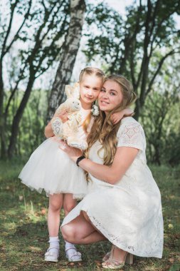 Hamile anne ve kızı yaz parkında yürüyorlar.