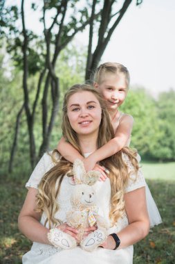 Hamile anne ve kızı yaz parkında yürüyorlar.