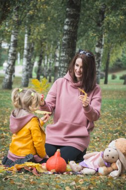 Anne ve üç yaşındaki kızı piknik için sonbahar parkında oynuyorlar.