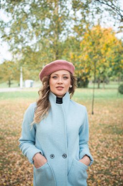 Güz parkında mavi ceketli ve bereli güzel bir kız.