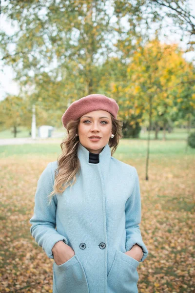 Güz parkında mavi ceketli ve bereli güzel bir kız.
