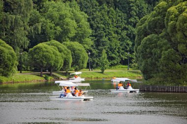 Moskova / Rusya 07 16 2019: Tsaritsino Yukarı Göleti ve pedallı tekne turistleri, yaz günü Tsaritsyno Park Müzesi 'nde yeşil ağaçlar üzerinde, Round Island yakınlarında Catamaran turistleri.
