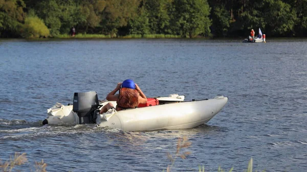 White catamaran Inflatable motor boat with 30 hp outboard motor and racer in camouflage lifejacket and blue helmet slow floating on water Race on river at Sunny summer day, outdoor sport competition — Stock Image White Catamaran Inflatable Motor Boat Outboard Motor Racer Camouflage Lifejacket Stock Photo