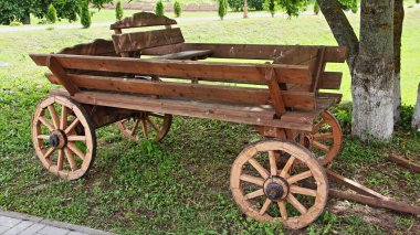 Kaliteli boş ahşap at arabası üzerinde ahşap tekerlekler Park Garden 'ın gölgesinde yeşil çimlerin üzerinde yaz günü Rus kırsal geçmişe ait nakliye tarzı.