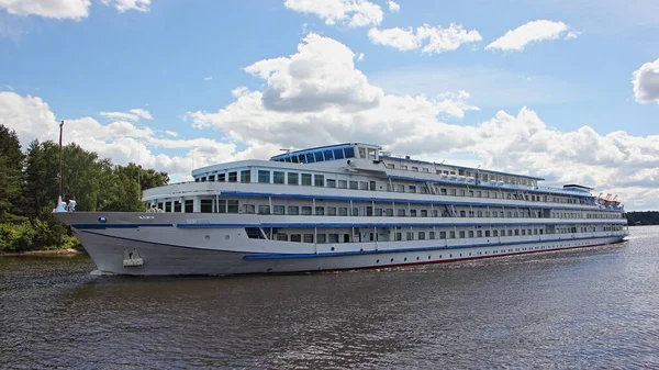 Beautiful large long four deck white cruise passenger ship floating on the river on a summer day on blue sky with clouds background, river cruises in Russia travel