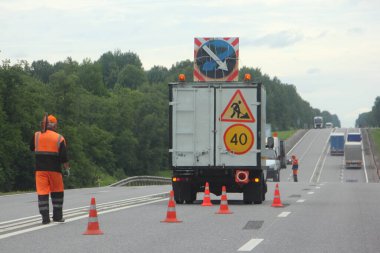 Yol onarımı, yatay yol işaretleme - turuncu işçi taşıyan kamyonet yolun sol şeridinde giysiler, turuncu güvenlik konileri, sapma yönü, hız limiti 40 km / saat ve yol çalışması
